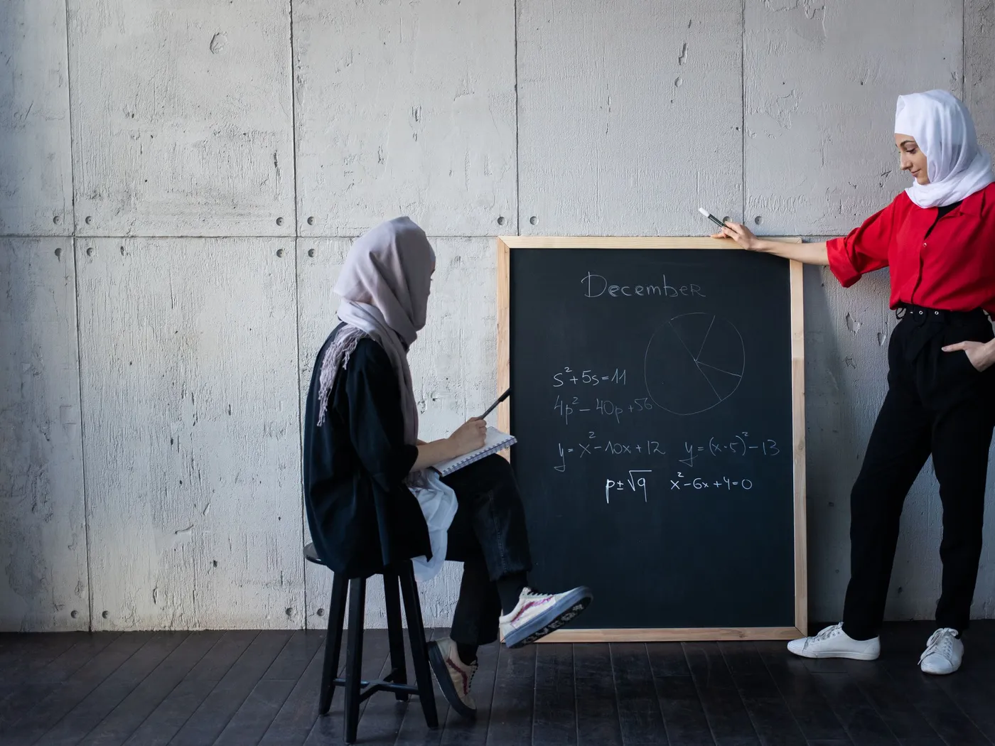 A tutor explaining at the board to a student
