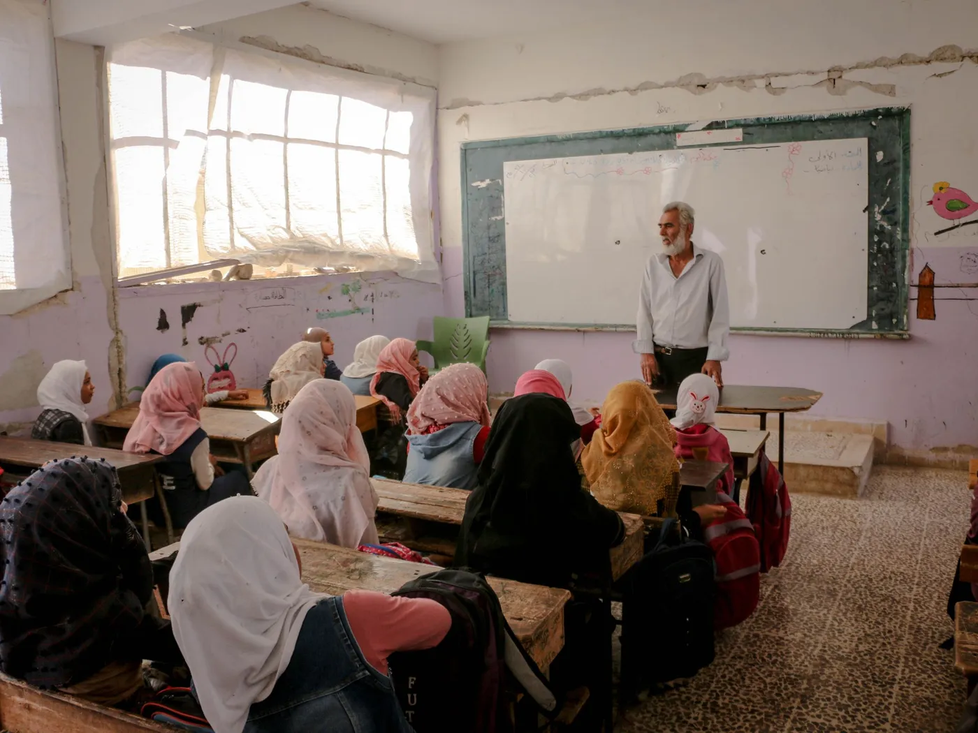 An older teacher standing in front of a full class